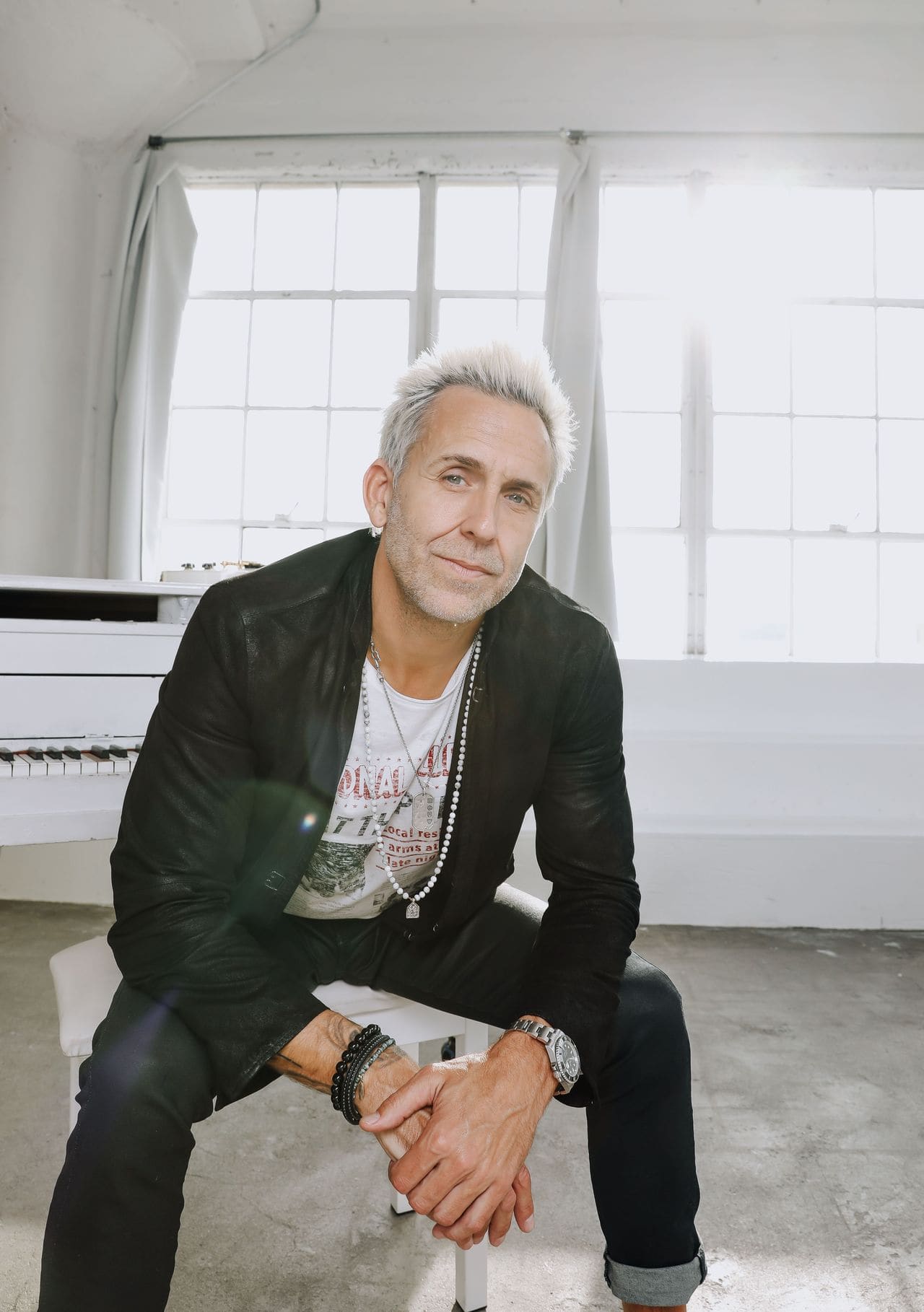 Wes Geer sitting at white piano, Rock to Recovery founder and music therapy pioneer